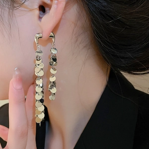 Détail de boucles d'oreilles pompons argentés à double couche avec sequins sur mannequin