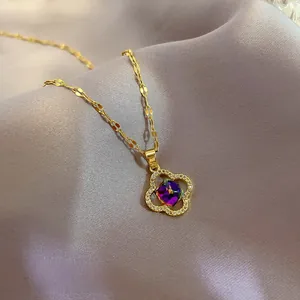 Detailed close-up of a gold four-leaf clover pendant with a radiant purple gemstone