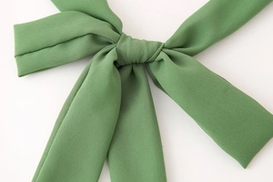 Détail du nœud en maille verte avec finition texturée sur une robe courte