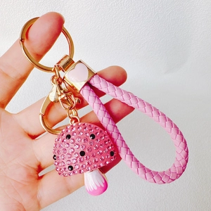 Detail of pink rhinestone mushroom keychain with gold hardware and woven strap