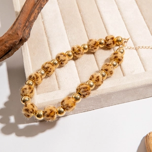 Détail des perles en peluche léopard et des perles métalliques dorées du collier