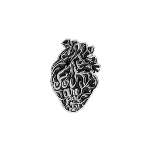 Macro detail of anatomical heart brooch with silver engraving You are part of me text