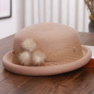 Close-up of a camel wool beret with elegant mesh veil and soft decorative spheres