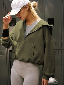Detail of dark green half-zip hoodie featuring ribbed cuffs and large front pocket