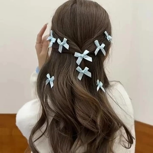 Light blue satin bow hair clips set styled on long brown wavy hair for women