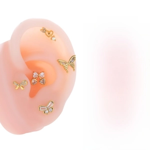 Close-up of golden butterfly and heart cartilage studs with sparkling zircon inlays