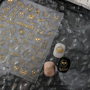 Makro-Detail von goldenen geprägten Halloween-Nagelstickern mit Kürbis- und Fledermausmotiven
