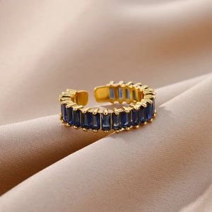 Macro shot of gold adjustable ring with row of deep blue rectangular zircons on satin