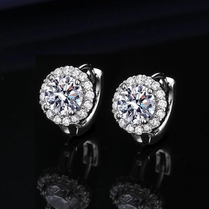 Macro view of silver round stud earrings with brilliant zircon stones on black background
