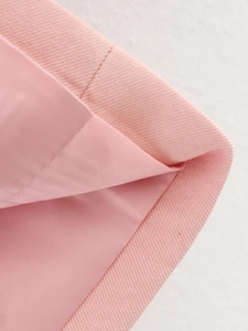 Dettaglio del tessuto in saia rosa con fodera abbinata e cuciture precise sul blazer