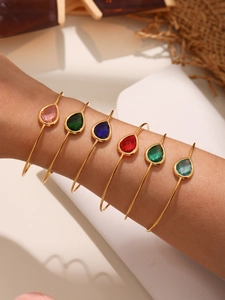 Detail shot of six stacked stainless steel bangles with colorful teardrop crystals