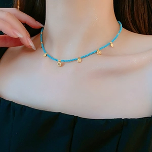 Gros plan d'un collier de perles turquoise avec petits pendentifs dorés sur modèle