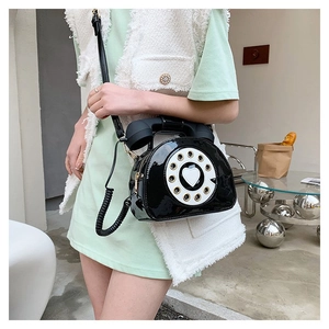 Detail of creative vintage telephone crossbody bag with glossy finish and heart dial