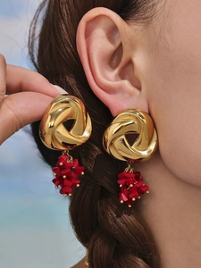 Detail of vintage gold twisted earrings with vibrant red bead clusters on a female model