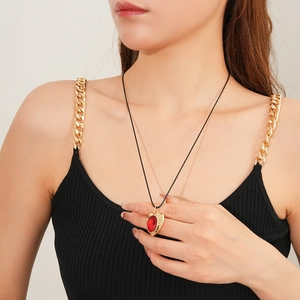 Detail of vintage gold necklace with red oval gemstone pendant worn by a model