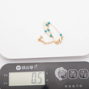 Vue détaillée d'un bracelet doré 18K avec perles bleues sur une balance, poids 0,5g