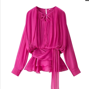 Macro view of magenta pleated fabric texture and ruffled hemline of this waist-tie top