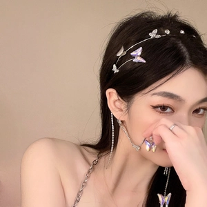 Detail view of model wearing a rhinestone butterfly headband, earrings, and ring set