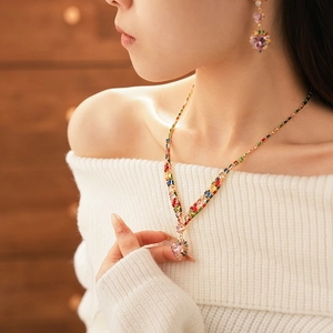 Model wearing a gold heart pendant necklace and colorful gemstone earrings set