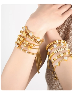 Detail of layered gold-plated beaded bracelets with butterfly charms and heart accents