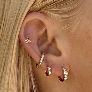 Close-up of S925 silver gold butterfly stud and geometric hoop earrings on ear