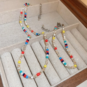 Colorful beaded choker necklace with silver metal accents on a beige linen jewelry tray