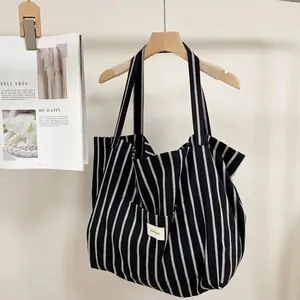 Detail of a large black and white striped canvas tote bag with a Bonjour logo label