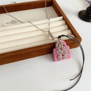 Détail du pendentif sac rose pailleté avec perles argentées sur une chaînette