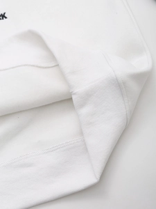 Close-up of white hoodie featuring ribbed cuffs and soft fleece lining material texture