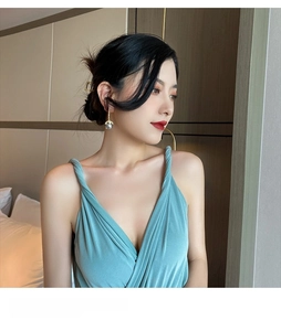 Elegant gold drop earrings with grey pearls worn with a deep V-neck blue pleated dress