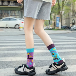 Close-up of vibrant purple and blue mismatched cotton socks with cartoon mushroom patterns