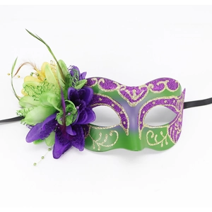 Detail of masquerade mask featuring purple fabric flowers and green feather accents
