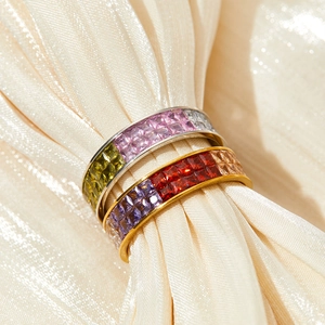 Rainbow gemstone eternity rings in gold and silver finish on silk fabric background