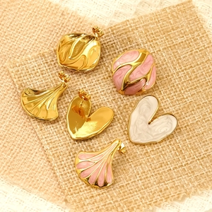 Golden heart and leaf enamel earrings set on textured beige fabric background