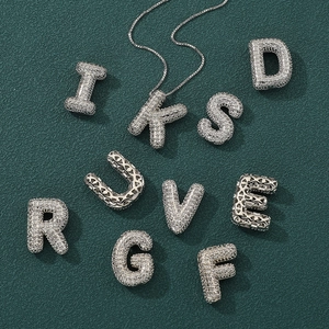 Macro view of iced out silver alphabet pendants with heart cutout details on the back