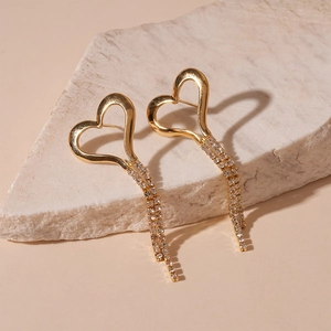 Detailed shot of golden heart fringe earrings with sparkling rhinestones on stone