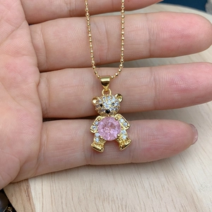 Detailed close-up of a golden bear pendant with pink zircon and micro-paved crystals