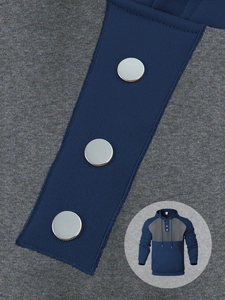 Detail of color-block hoodie showing metallic buttons and knit fabric texture