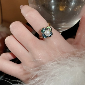 Detailaufnahme eines floralen Goldrings mit weißer Perle und schimmernden Muschel-Blüten