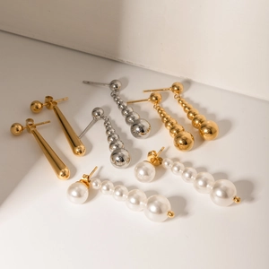 Detailed view of assorted 18k gold stainless steel drop earrings and tiered pearl pendants