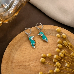 Exquisite kingfisher earrings with blue enamel finish on a rustic wooden tray decoration