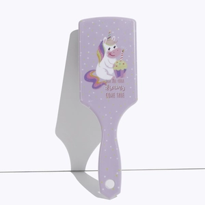 Detail view of purple unicorn hairbrush with white polka dots and motivational quote