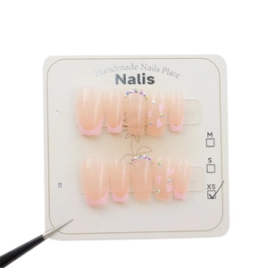 Handmade pink French press-on nails with iridescent rhinestones and heart accents