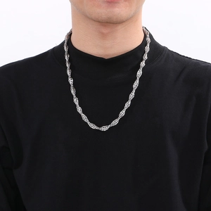 Gros plan d'un collier chaîne torsadée argenté porté par un mannequin pour un look