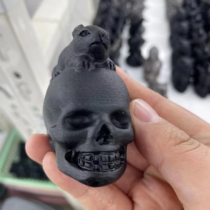 Detailed close-up of a matte black obsidian puppy dog carving with skull motif detail