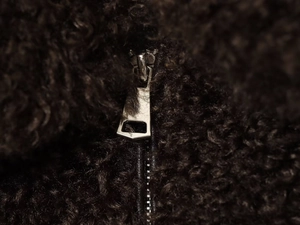 Detailed close-up of the silver metal zipper on a dark brown fleece jacket