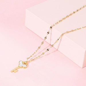 Detail view of a gold key necklace with white shell inlay on a twist chain link