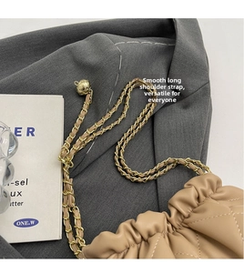 Detail of quilted beige bucket bag with gold chain strap and spherical adjustment buckle