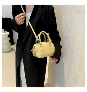 Detail of a yellow bowling handbag worn over a black blazer for a stylish contrast