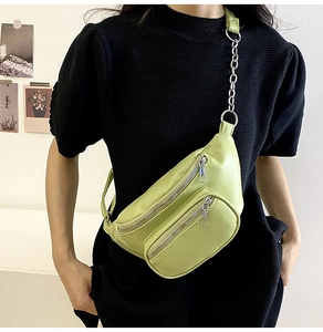 Close-up of light green PU leather chest bag with chain strap and dual zipper compartments